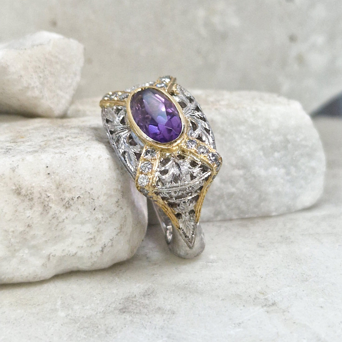 L'anello di tre quarti su una pietra bianca: l'ametista nel castone d'oro sopra il traforo di foglie in argento