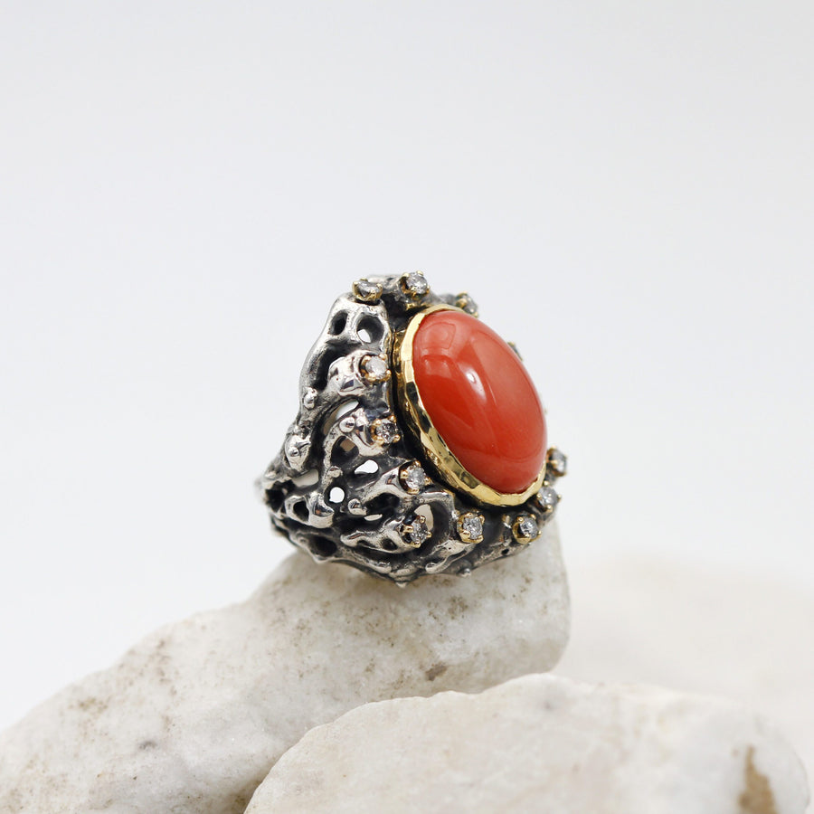 The hammered gold rim closing over the coral, seen almost edge on