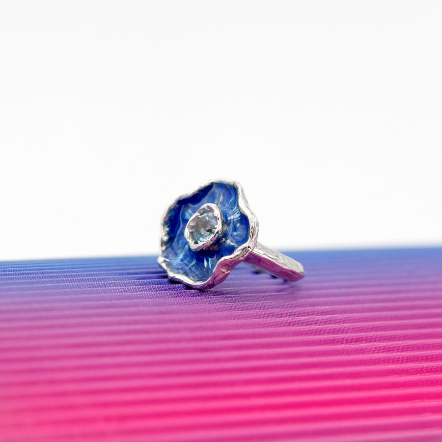 Su un fondo rigato di blu e rosa, l'anello in piedi visto di tre quarti