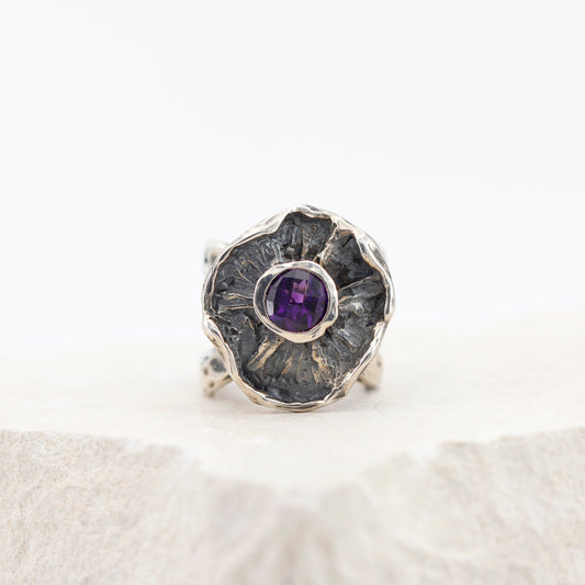 L'anello di fronte: la corolla d'argento con l'interno scuro e l'ametista al centro