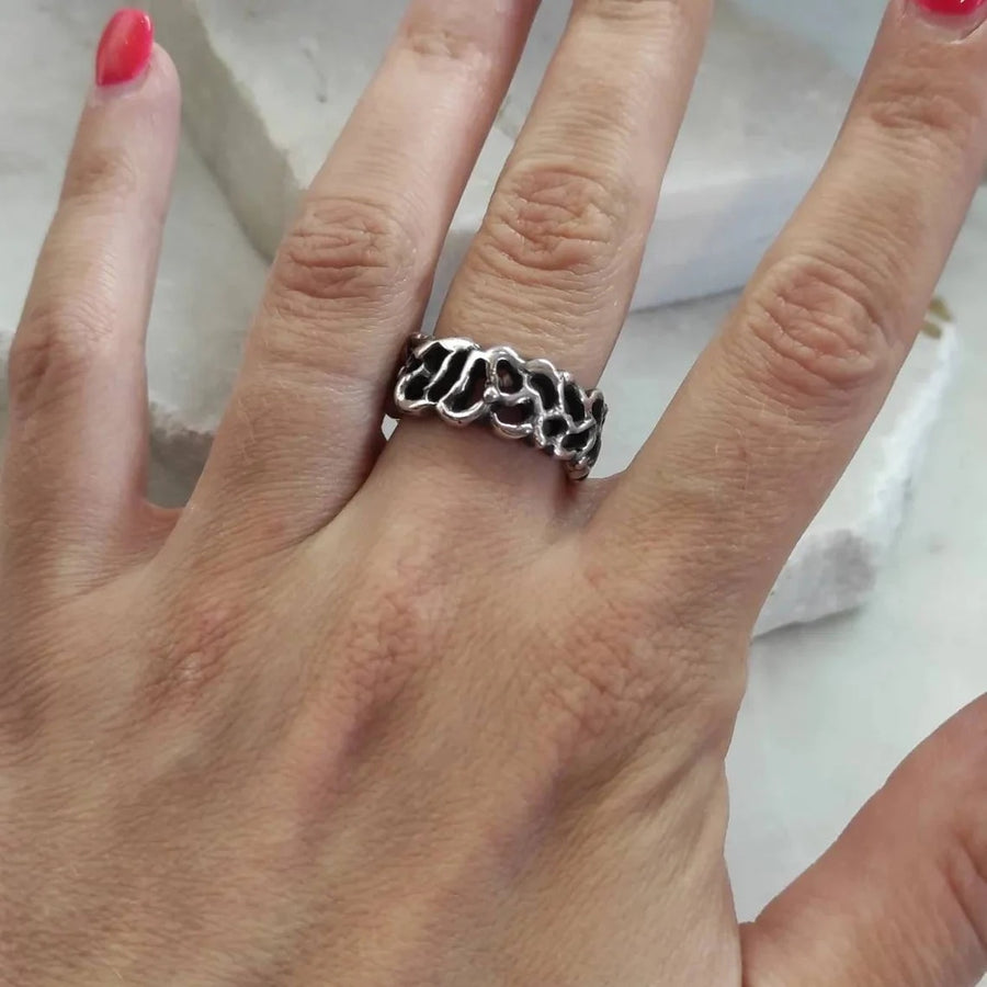 The ring worn, from another angle: the light ribs above the black grounds.