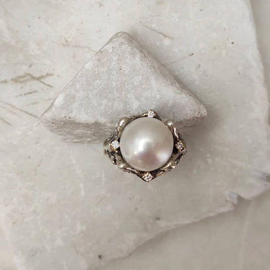 L'anello dall'alto: i quattro diamanti nei castoni d'oro disposti attorno alla perla