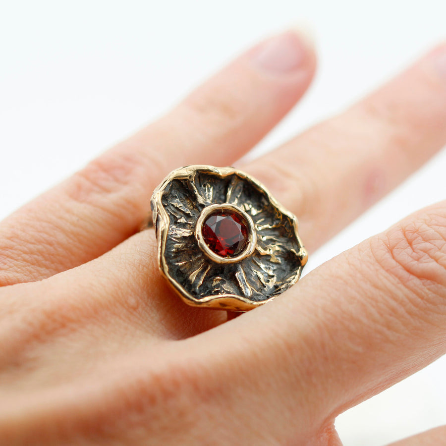 L'anello al dito ripreso da vicino, il rosso del granato sul fondo scuro