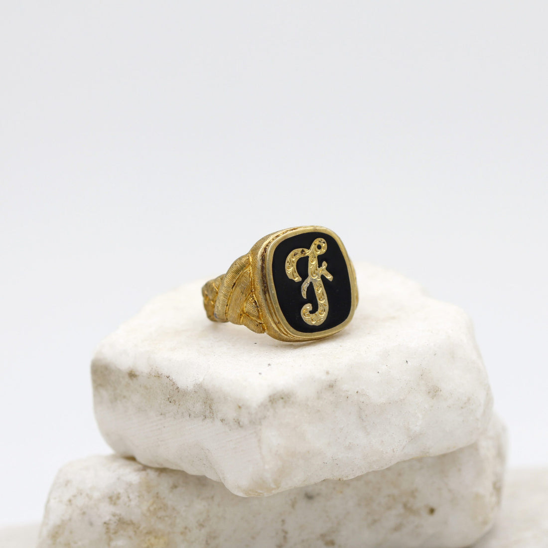 Anello da uomo in argento dorato con l'iniziale in corsivo su fondo nero, veduta di tre quarti