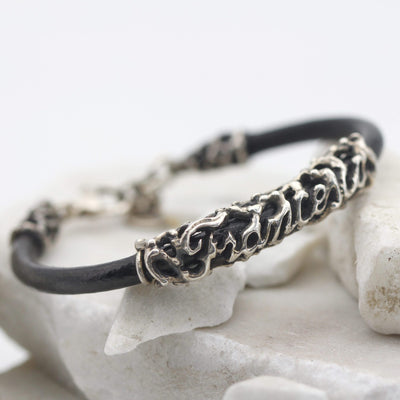 Il bracciale appoggiato di sbieco su una pietra bianca, con l'elemento del nome al centro del cordoncino