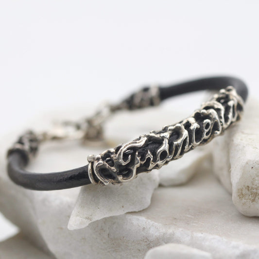 Il bracciale appoggiato di sbieco su una pietra bianca, con l'elemento del nome al centro del cordoncino