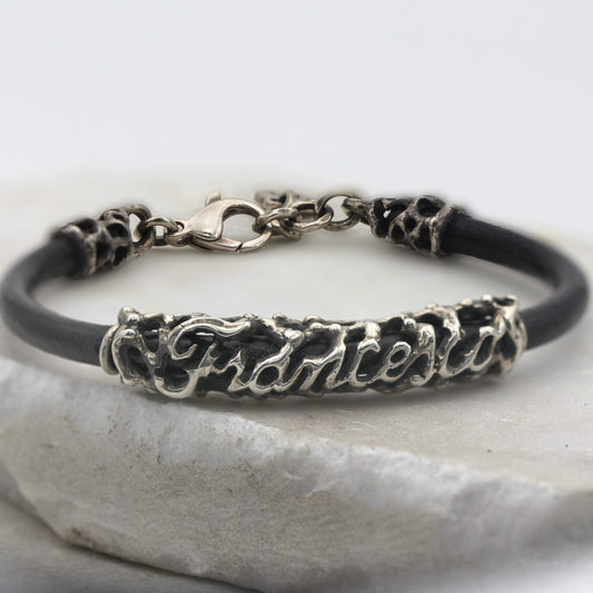 Veduta frontale del bracciale chiuso: il moschettone in alto, il nome in corsivo in basso