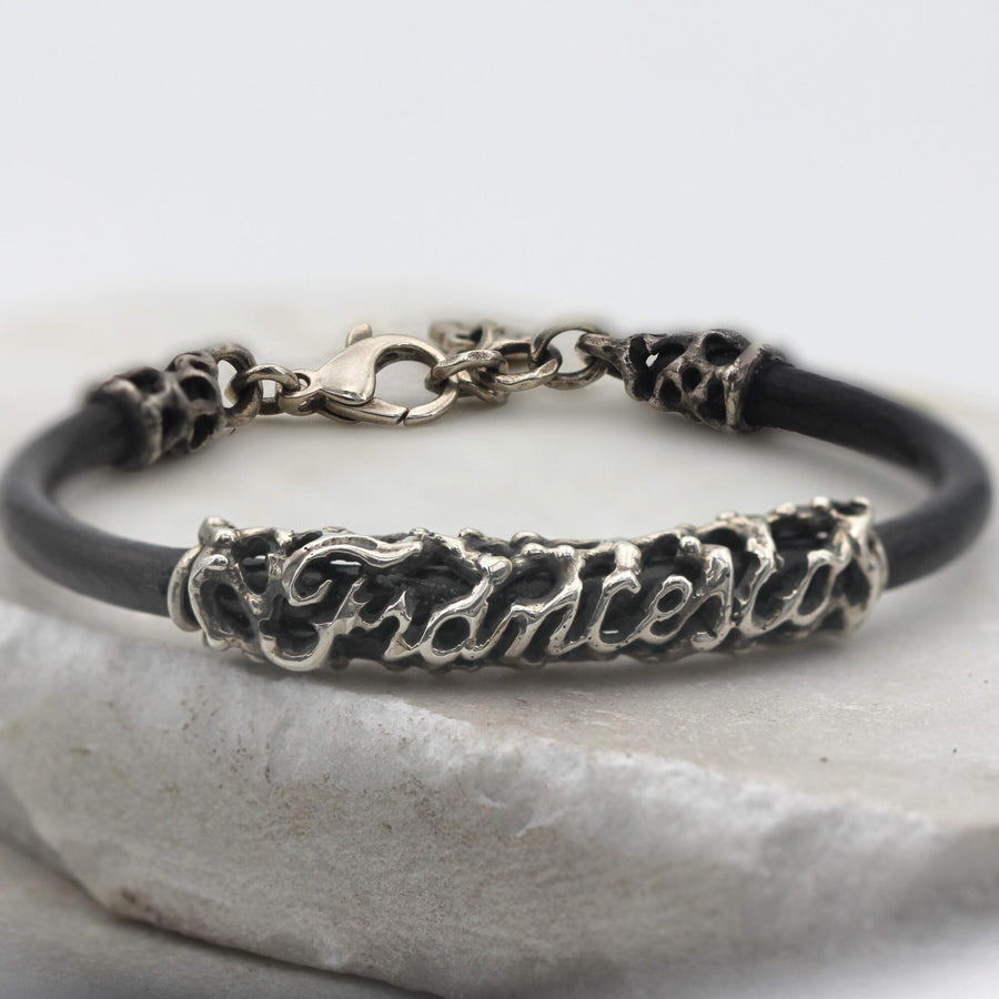 Veduta frontale del bracciale chiuso: il moschettone in alto, il nome in corsivo in basso