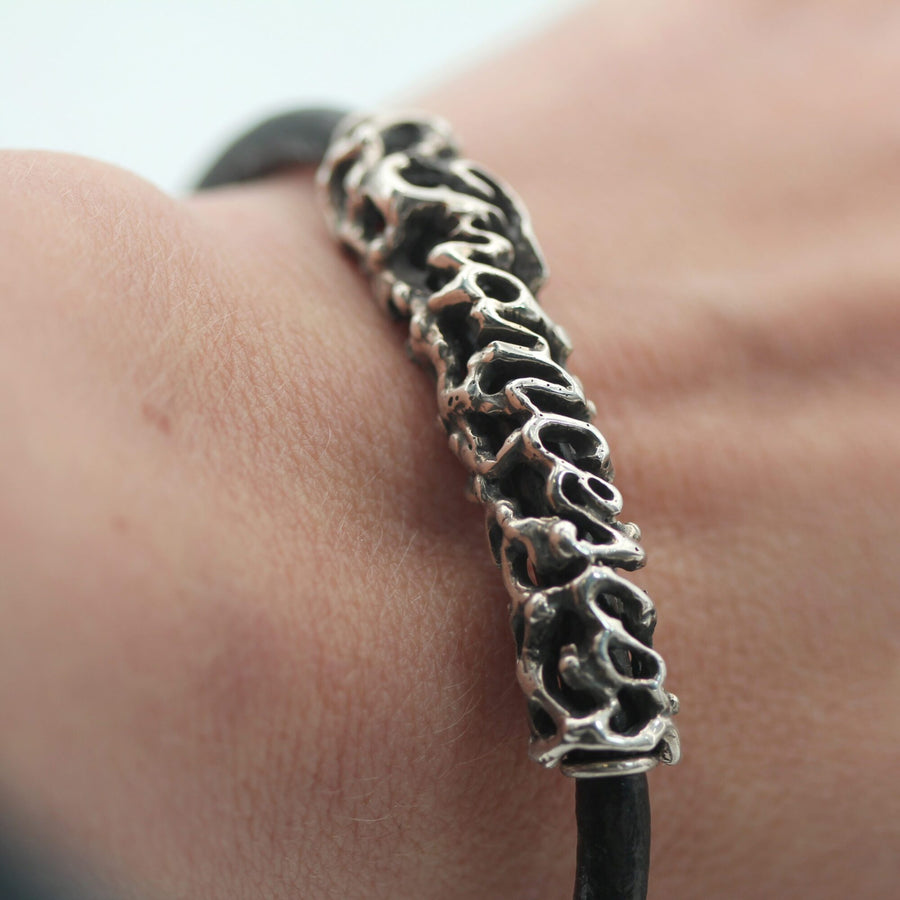 Il bracciale al polso: il nome visto di taglio, con i vuoti fra una lettera e l'altra