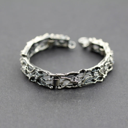 Il bracciale chiuso ad anello su fondo grigio, con il moschettone aperto in alto