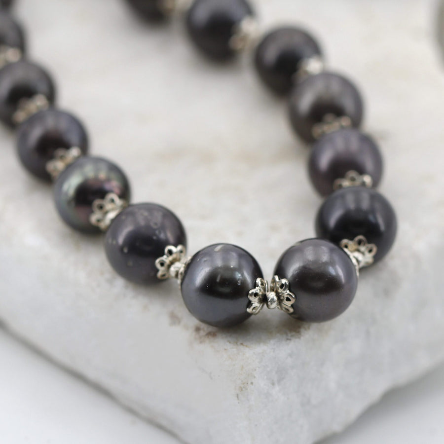The pearls close up: the dark grey turns to green and aubergine, and between one and the next the silver flower