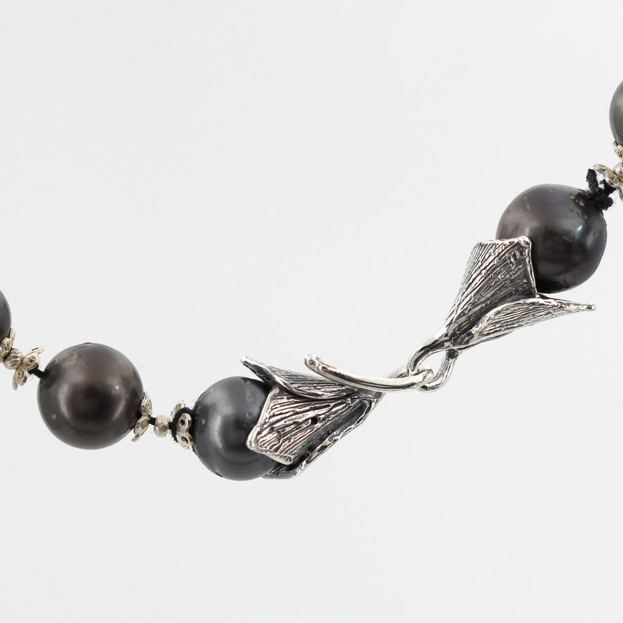 The raised veins on the two leaves, and the dark thread that runs between the pearls