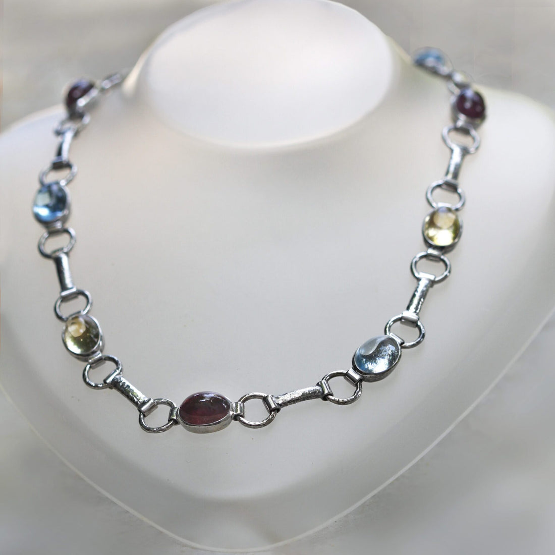 La collana chiusa ad anello su un espositore da collo: la sequenza dei colori si ripete, rosso scuro, azzurro, giallo limone