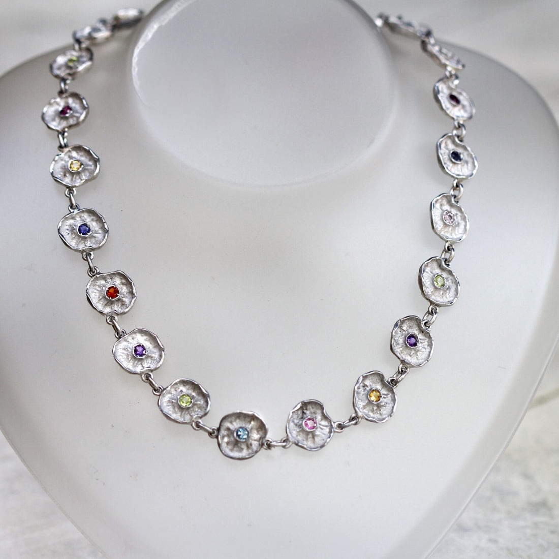 The whole necklace on the neck display: the twenty-two silver corollas close the circle one after the other, each with its own stone at the centre
