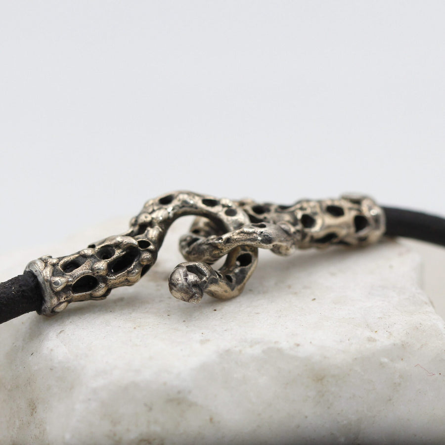 The hook unfastened, with the two ends of the cord laid out on the marble