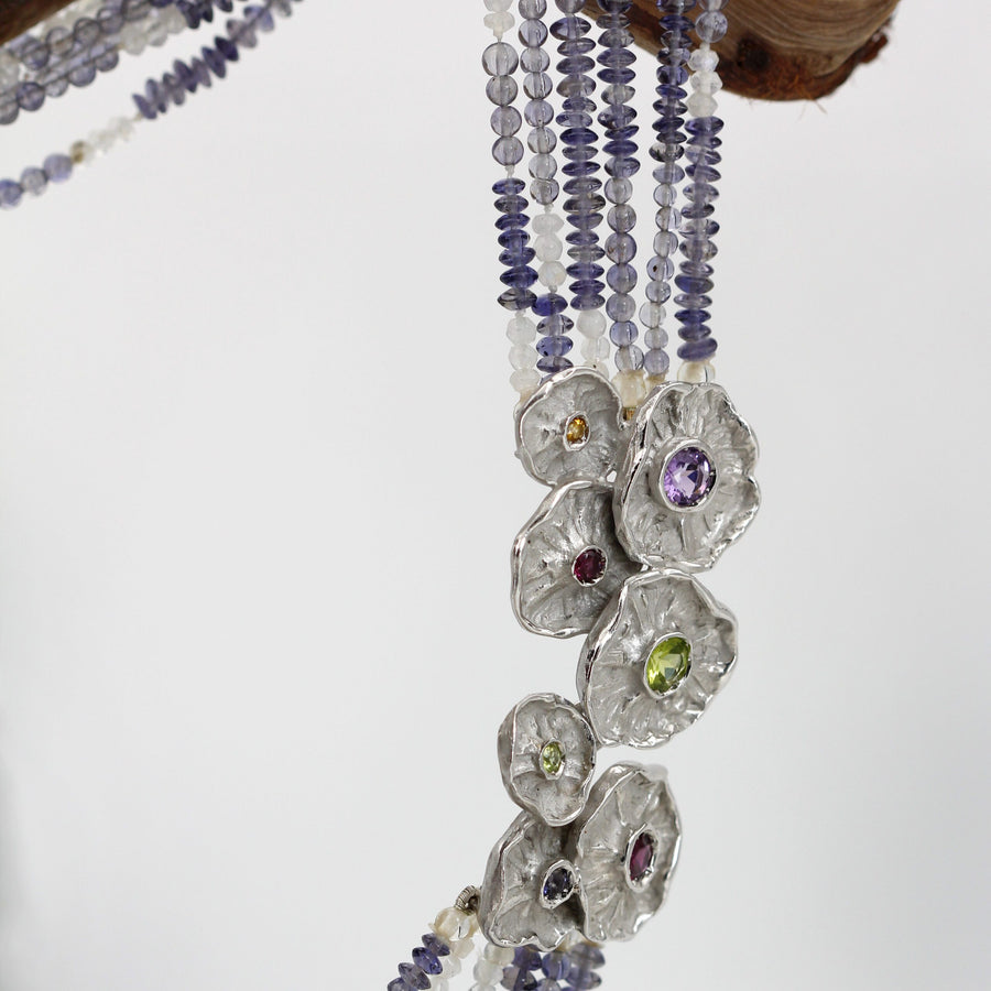 The necklace hanging from a branch: the six strands run down parallel as far as the flowers