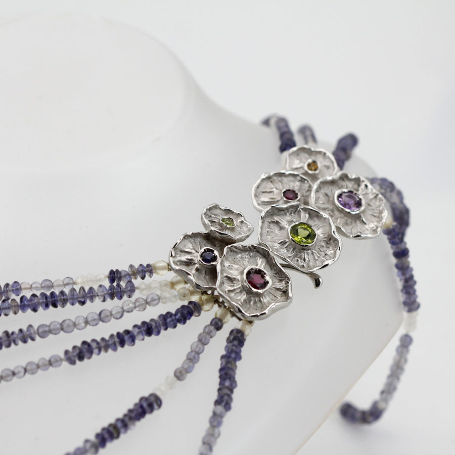 The clasp resting on the bust: all the strands gather on the same side of the neck