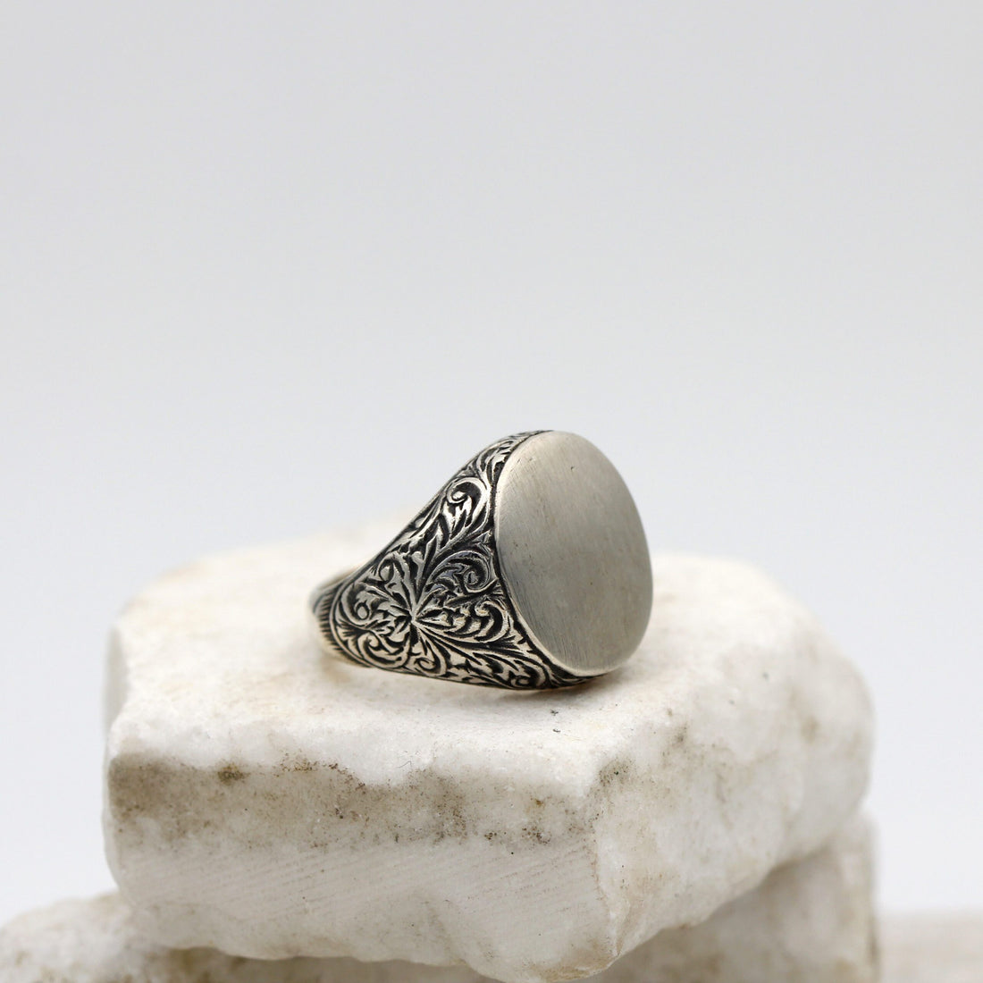 Anello da uomo in argento con la testa ovale liscia e le spalle incise a bulino, veduta di tre quarti
