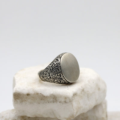 Anello da uomo in argento con la testa ovale liscia e le spalle incise a bulino, veduta di tre quarti
