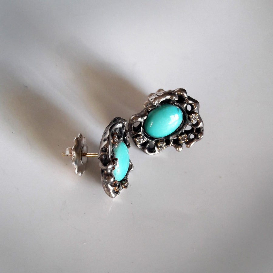 Three-quarter view with one earring open: the gold post, the butterfly back slipped off and the diamond bezels seen from the side