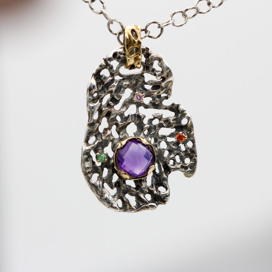 The pendant from the front, hanging: the net of openings and the amethyst at the centre