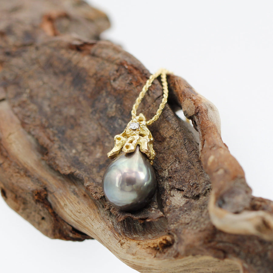 The pendant resting on a piece of driftwood, wide view