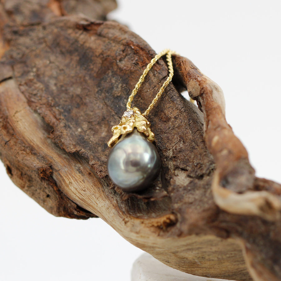 The pendant hanging from a piece of driftwood, wide view (the chain is not included)