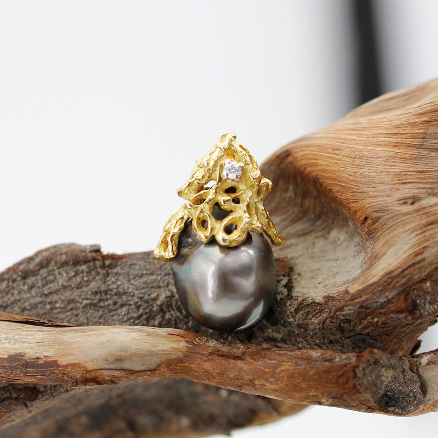 Close-up: the irregular outline of the pearl and the bronze, green and pink iridescence