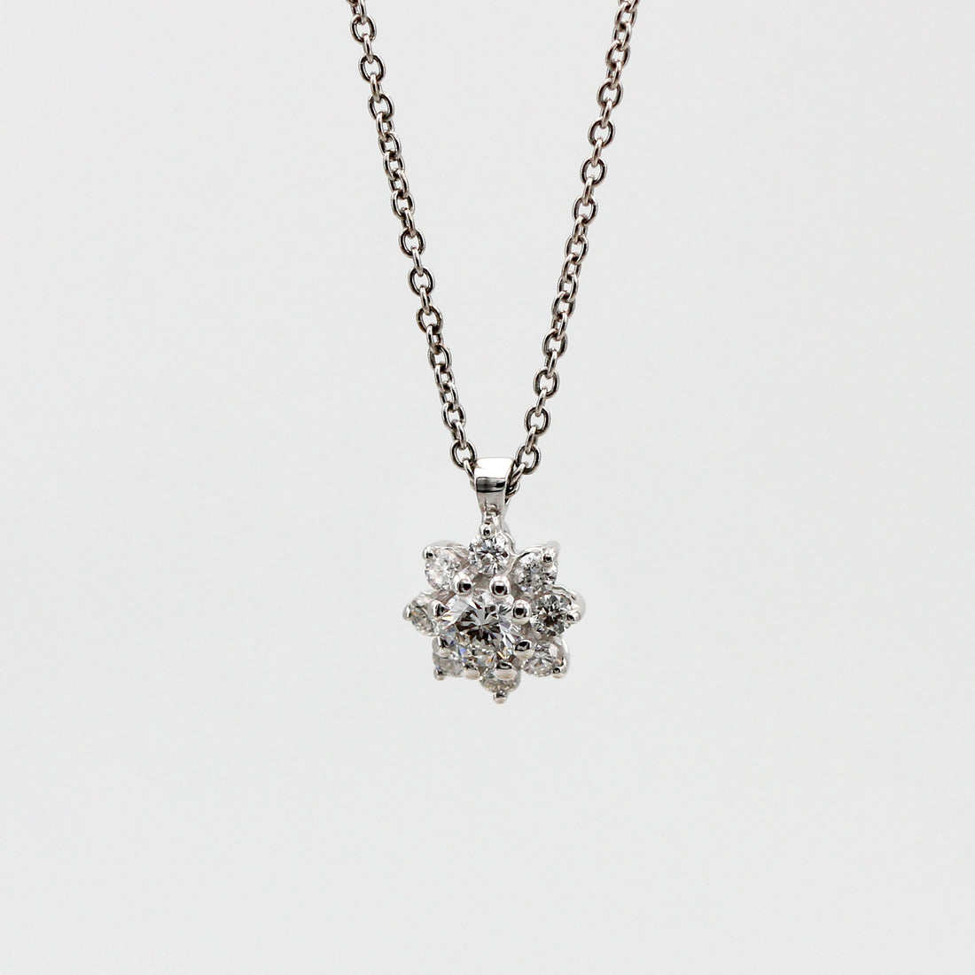 The pendant hanging from the chain on a grey background, front view