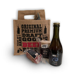 La shopper di juta con la bottiglia e i salumi accanto