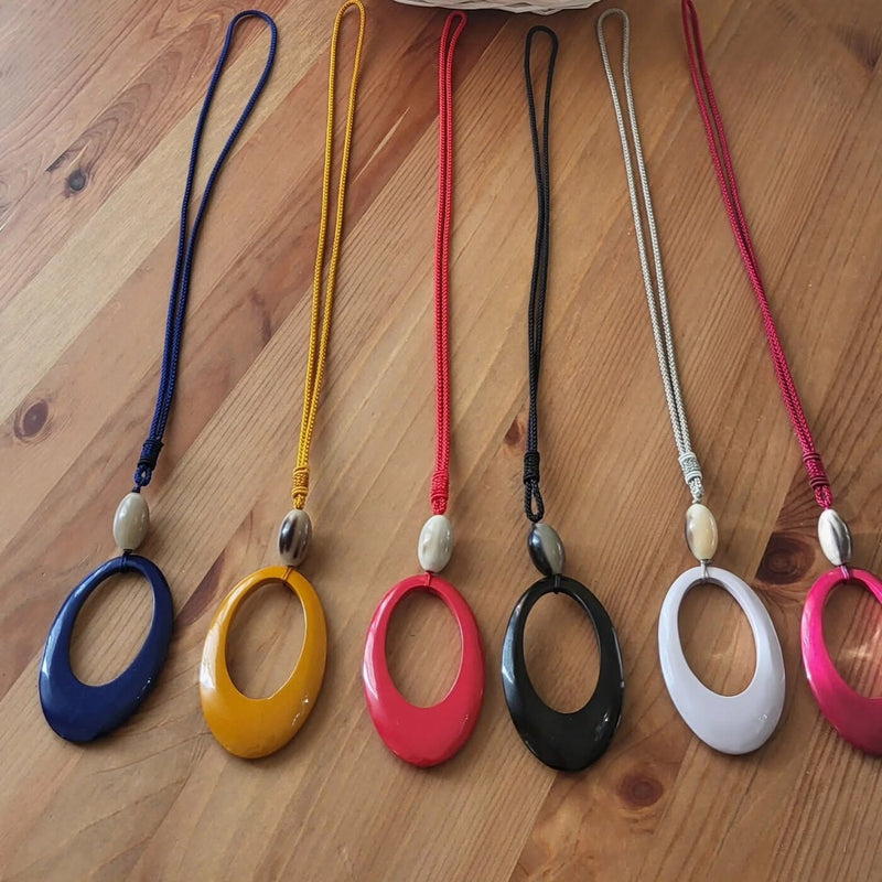 Sei ciondoli ovali su cordino, ognuno di un colore: blu, giallo, rosso, nero, bianco, rosa