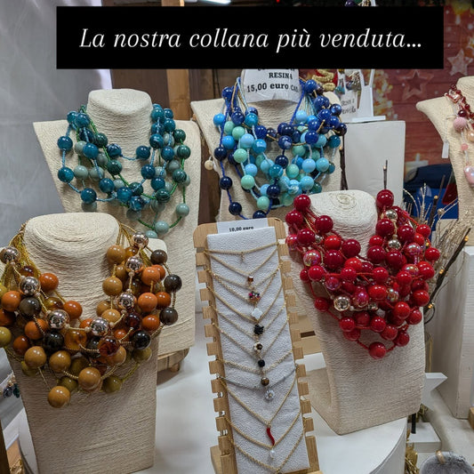 Espositori di collane di resina a più fili al banco, con il cartello «la nostra collana più venduta»