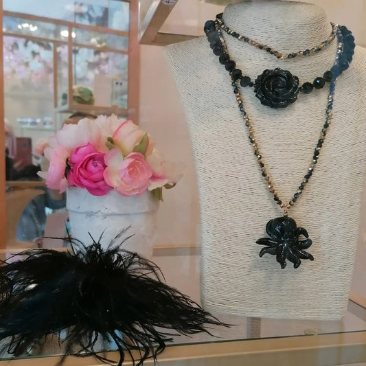 Girocollo di cristalli neri e dorati con rosa nera intagliata al centro, in vetrina accanto alla collana lunga