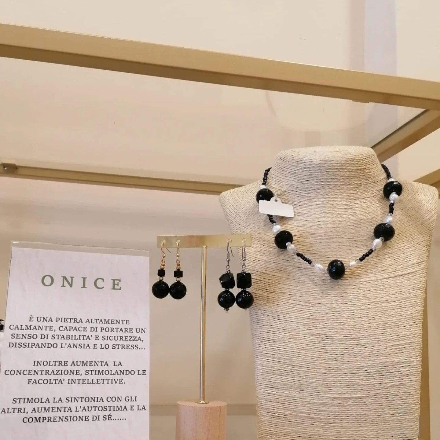 Vetrina dell’onice: girocollo di sfere di onice sfaccettato con perle bianche, due paia di orecchini e il cartoncino sulla pietra