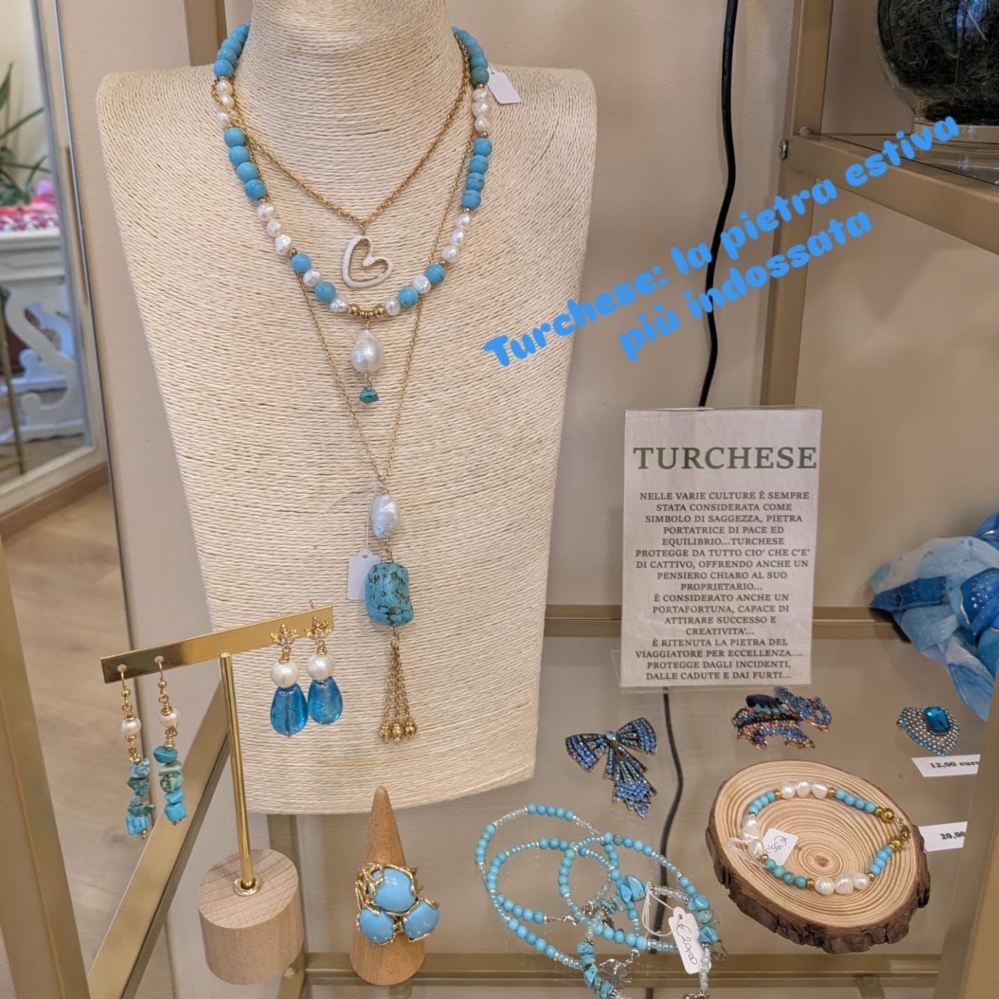 Vetrina del turchese: collana di turchese e perle, catene con cuore di madreperla e nappina, orecchini, anello e bracciali, con il cartoncino sulla pietra