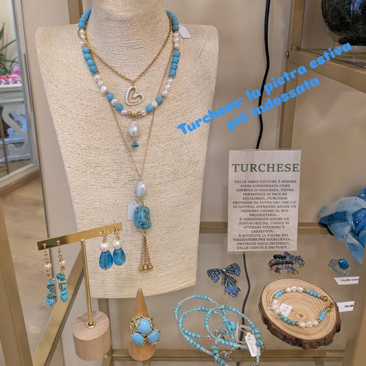 Vetrina del turchese: collana di turchese e perle, catene con cuore di madreperla e nappina, orecchini, anello e bracciali, con il cartoncino sulla pietra