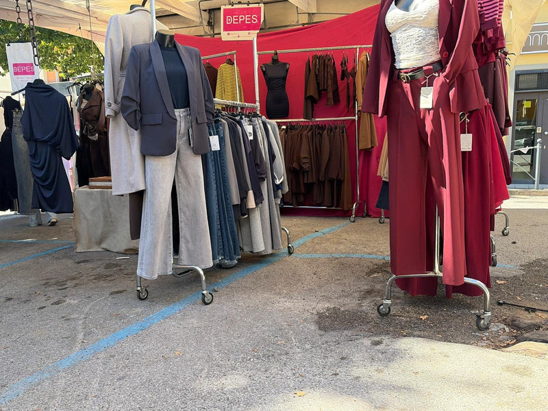 Il banco Asky visto di fronte, manichini e stender di abbigliamento da donna sotto il tendone