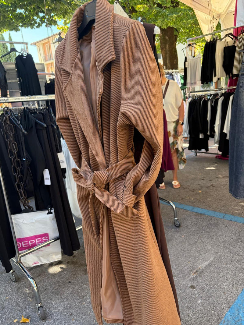 I manichini del banco con abito bordeaux, blazer e pantaloni chiari, davanti al telo rosso