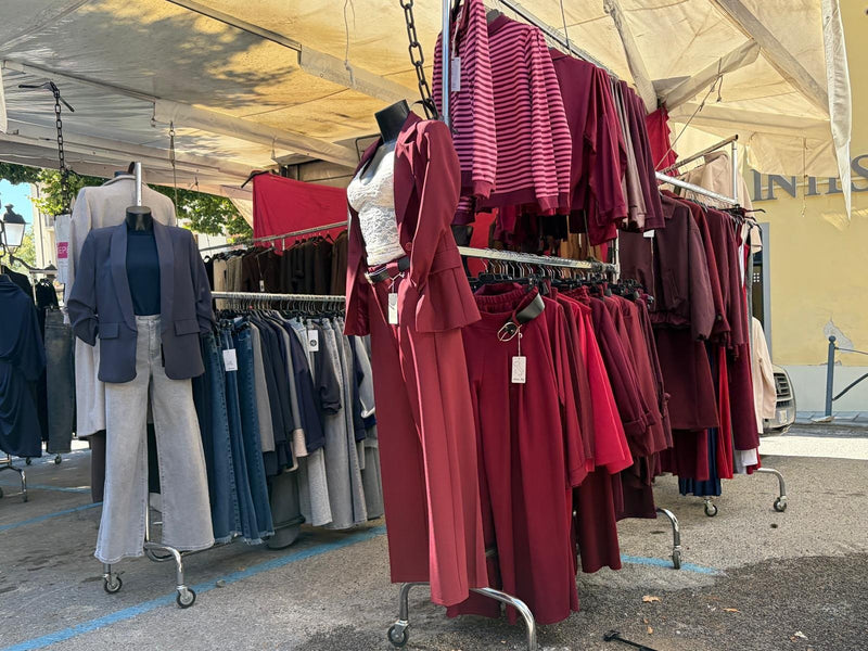 Il banco Asky sotto il tendone: manichini con blazer e abito bordeaux, e gli stender dell'abbigliamento da donna