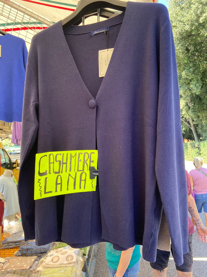 Un cardigan blu in cashmere e lana appeso, col cartello scritto a mano