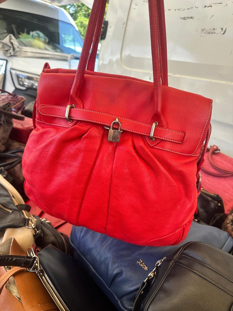 Una borsa rossa con i manici lunghi e la chiusura a fibbia, appesa al banco