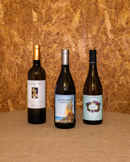 Le 3 bottiglie della selezione «Bianchi Selezione Bottegone» in piedi davanti al fondo del set: Vermentino Is Argiolas, Sul Vulcano Bianco Donnafugata e Sharis Livio Felluga.