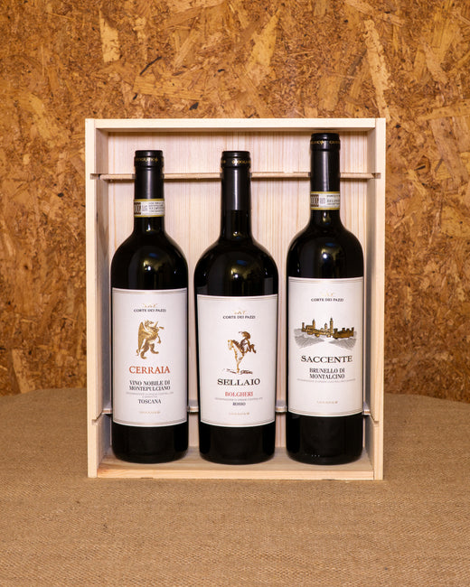 Le tre bottiglie nella cassetta di legno aperta: Bolgheri Rosso Sellaio, Nobile di Montepulciano Cerraia e Brunello di Montalcino Cerraio.