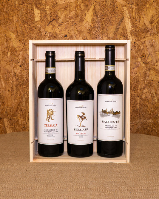 Le tre bottiglie nella cassetta di legno aperta: Bolgheri Rosso Sellaio, Nobile di Montepulciano Cerraia e Brunello di Montalcino Cerraio.
