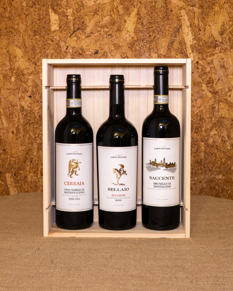 Le tre bottiglie nella cassetta di legno aperta: Bolgheri Rosso Sellaio, Nobile di Montepulciano Cerraia e Brunello di Montalcino Cerraio.