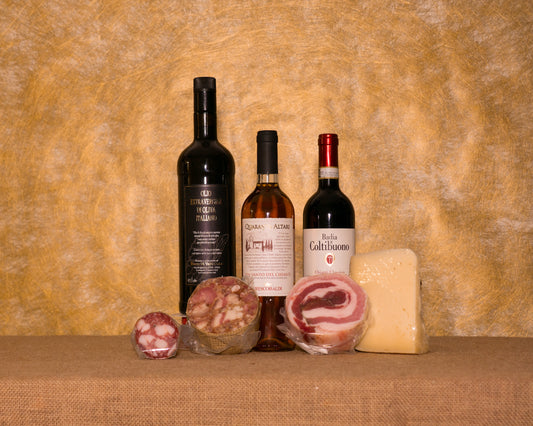 I 7 prodotti del cesto «Dispensa del Nonno in Toscana» disposti sul fondo di juta, fra cui Chianti Classico DOCG Badia a Coltibuono, Vin Santo del Chianti Quaranta Altari e Pecorino “Paglione” 8 mesi, e gli altri.