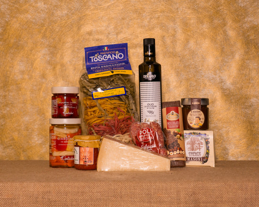 I 10 prodotti del cesto «Raffinate Delizie» disposti sul fondo di juta, fra cui Tagliatelle 5 sapori Pastificio Toscano, Olio EVO Italiano De Carlo e Ragù di Capriolo, e gli altri.
