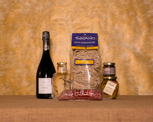 I 7 prodotti del cesto «Tartufaio Serio» disposti sul fondo di juta, fra cui Pecorino Moliterno al tartufo, Salsa tartufata Naturbosco e Pici al tartufo Pastificio Toscano, e gli altri.
