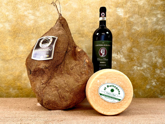 I 3 prodotti del cesto «Tesori di Toscana» disposti sul fondo dorato del set: il prosciutto toscano intero, la forma di pecorino «Serbo» e la magnum di Chianti Classico Riserva Contessa Radda.