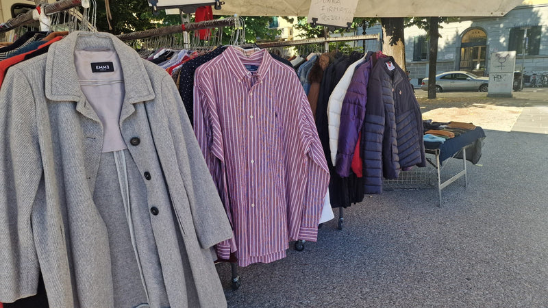 Un cappotto grigio, una camicia a righe e i piumini appesi allo stender